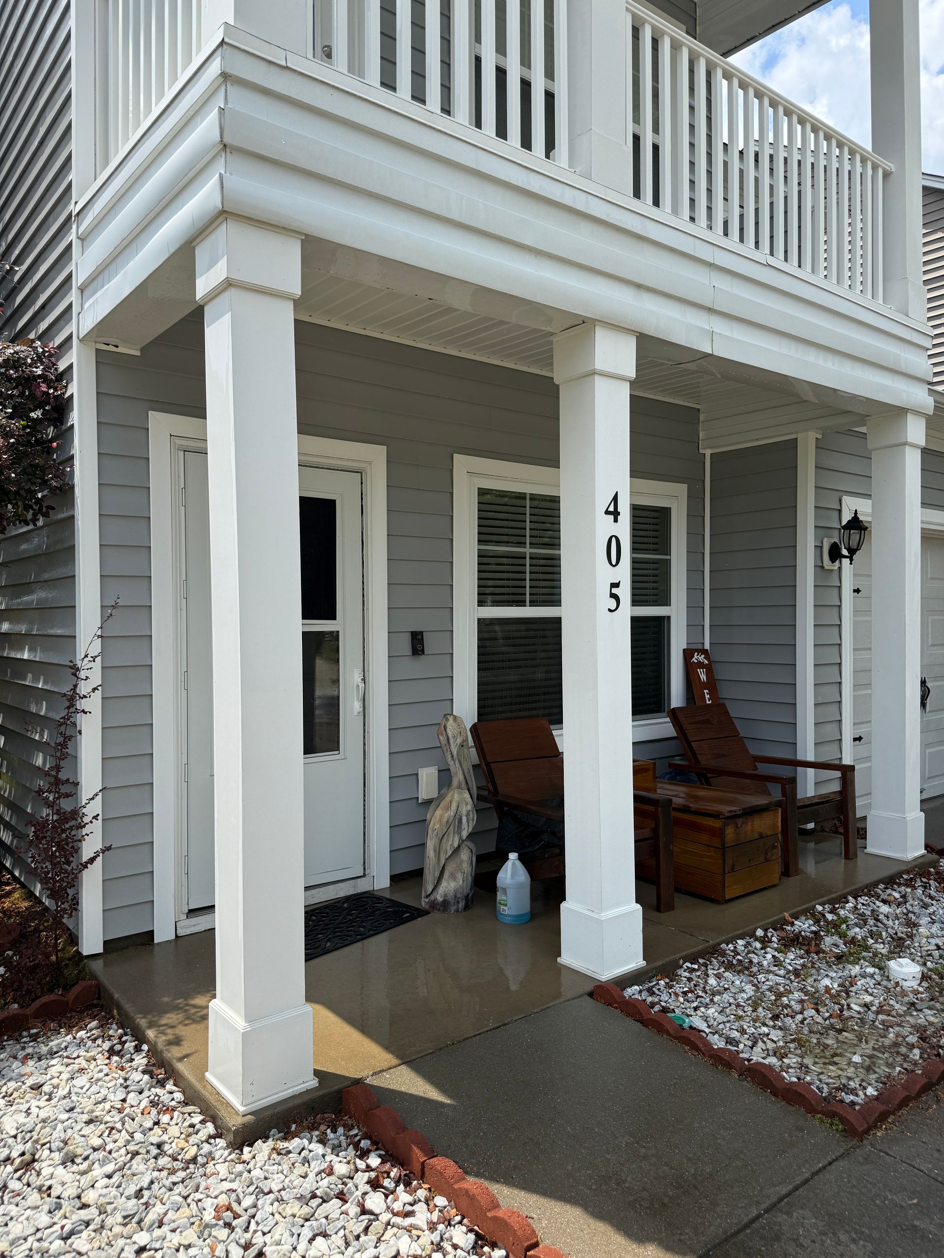Front porch with white siding, two chairs, and house number 405 beside a snowy walkway.