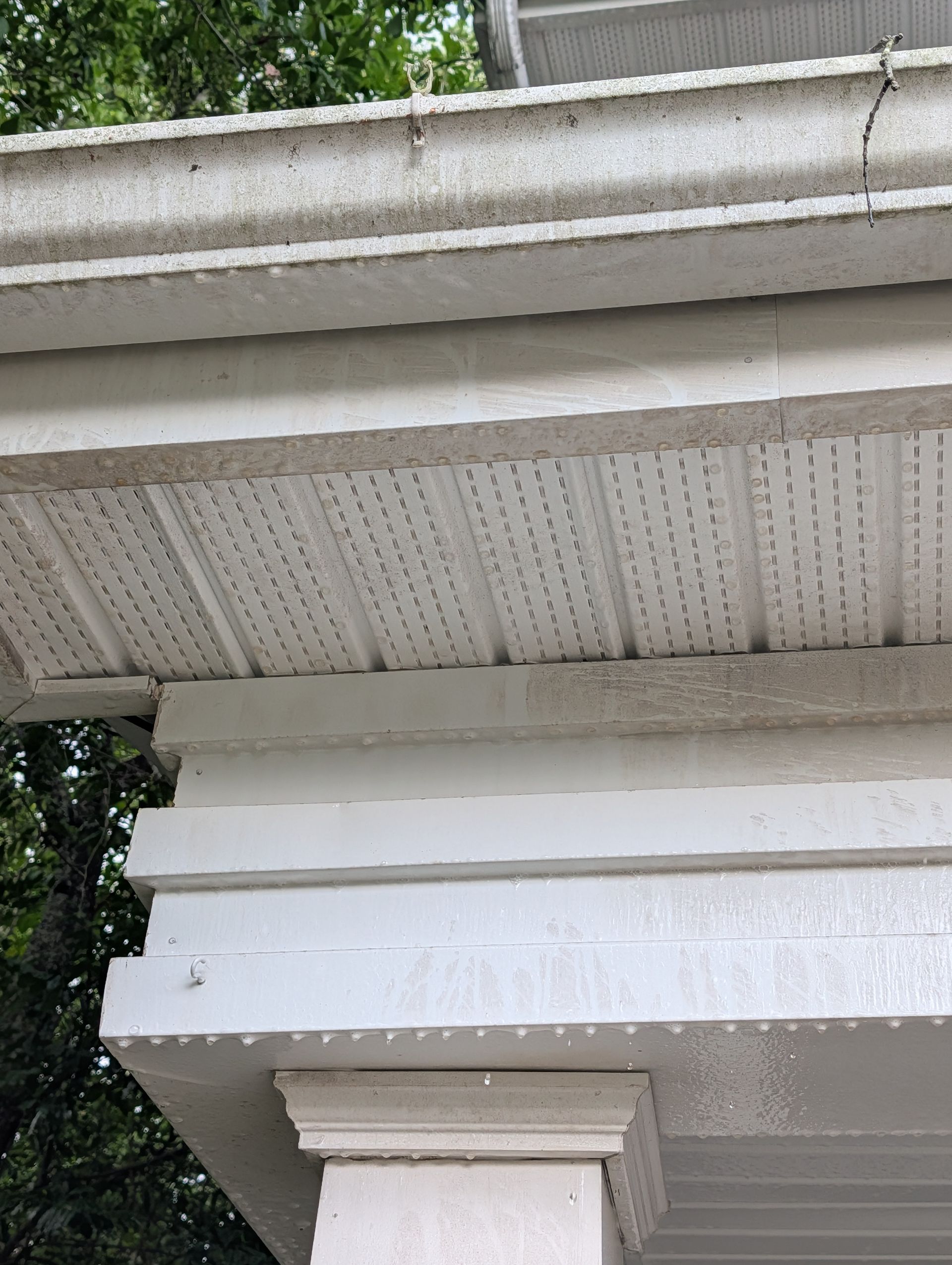 White house eaves with soffit, trim, and decorative column detail beneath the roofline