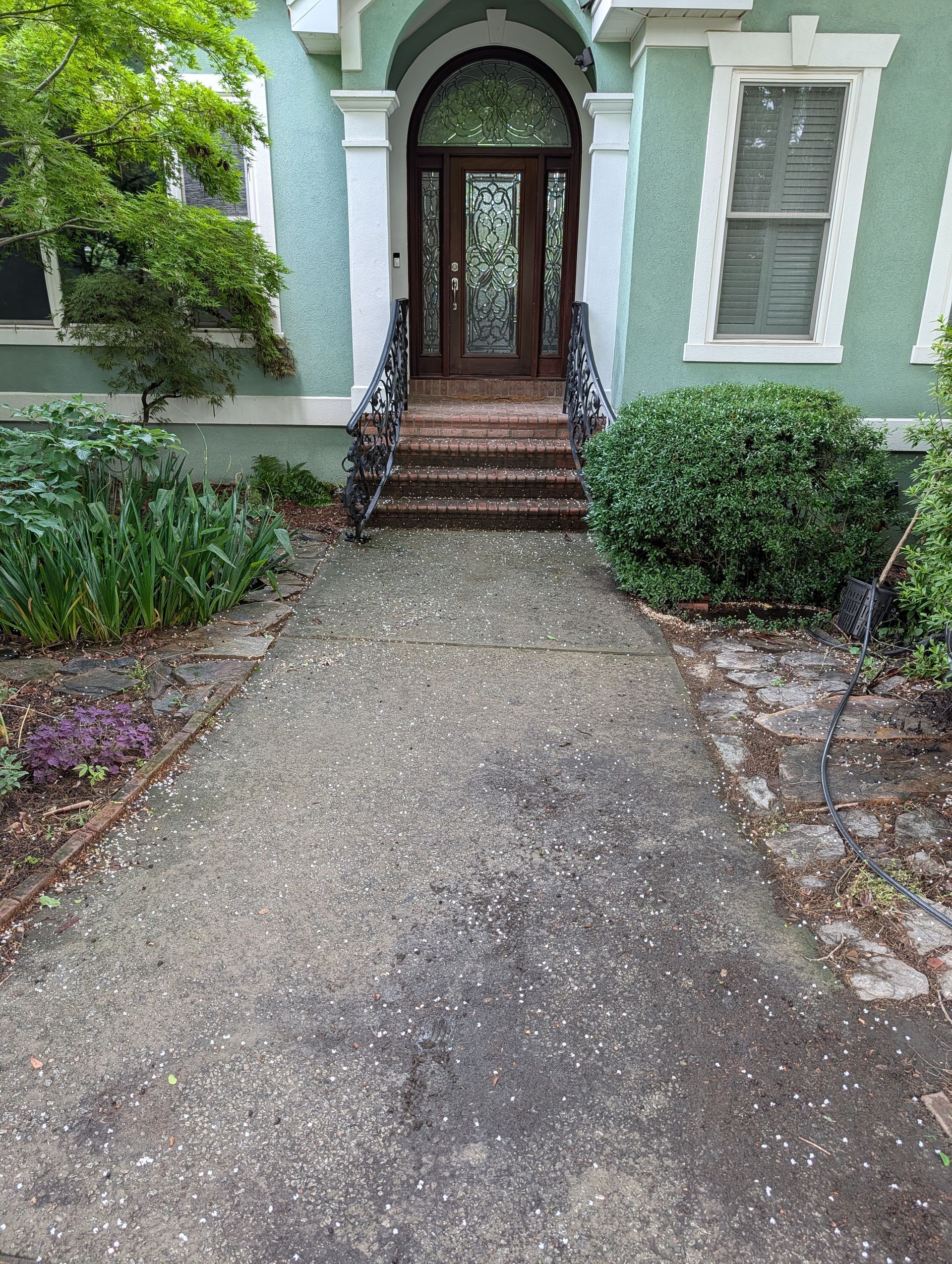 Concrete path leading to a green house entrance with steps and an arched doorway
