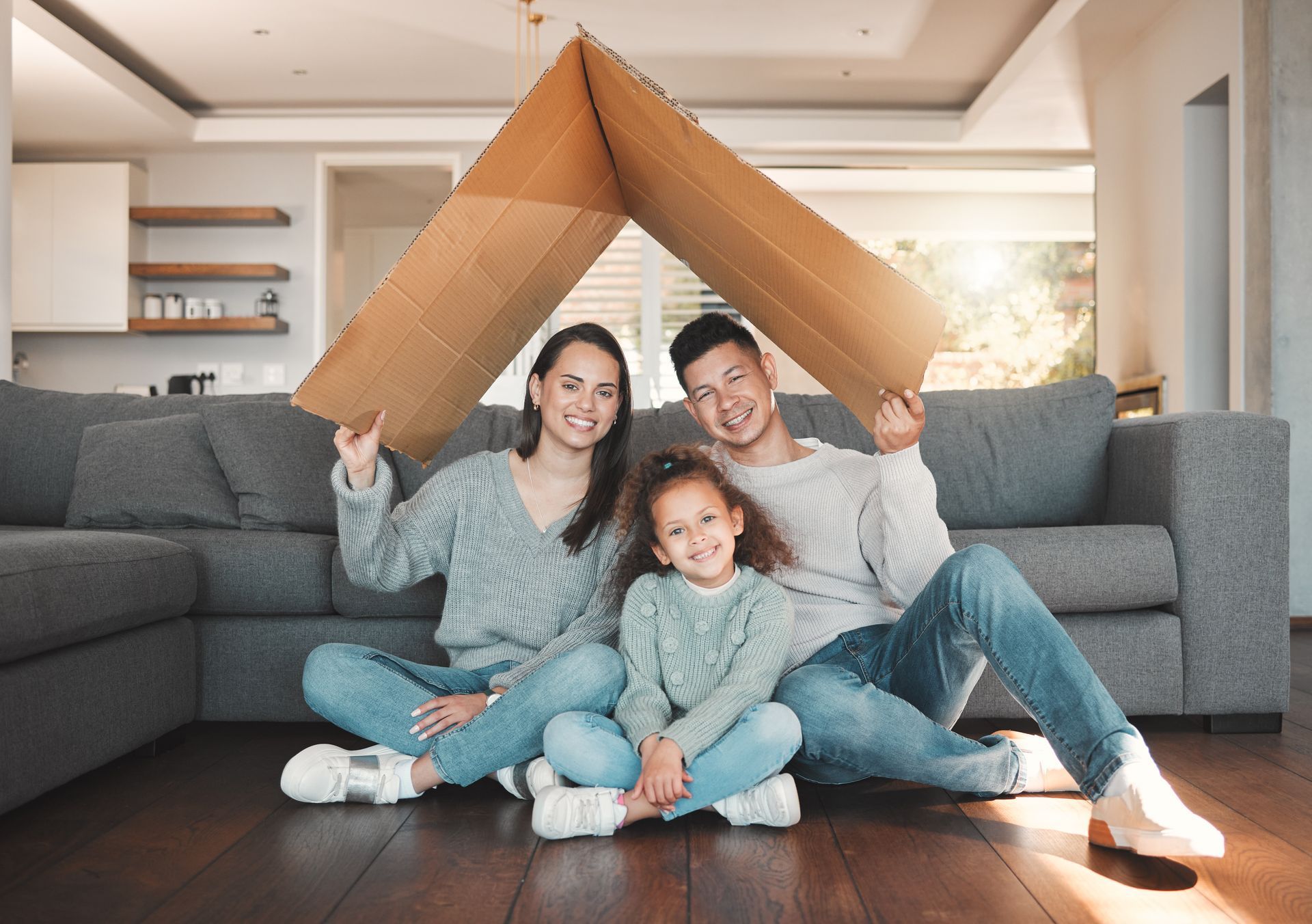 Family smiling under a cardboard fort in a living room