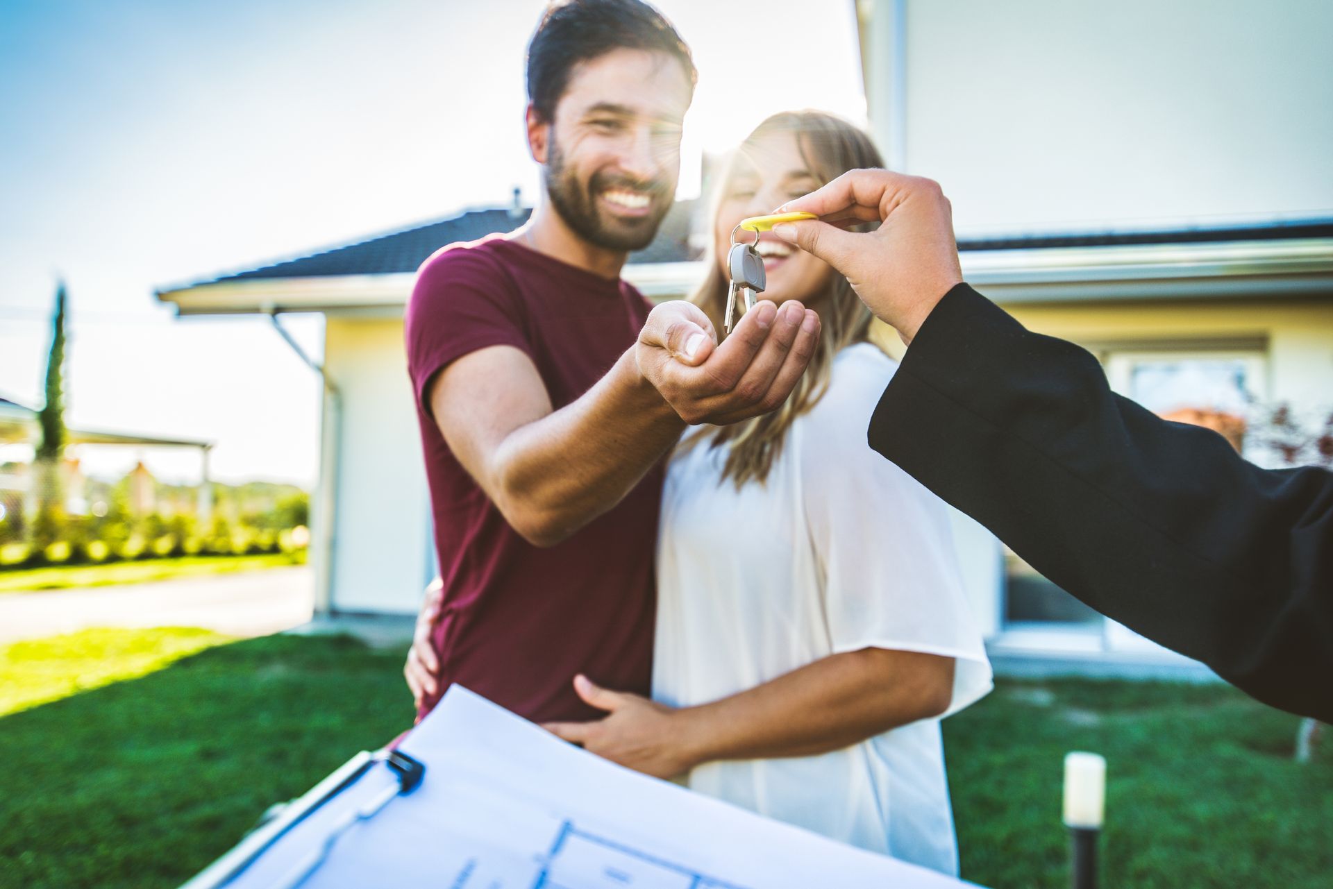 A couple receiving house keys from an agent outside a new home