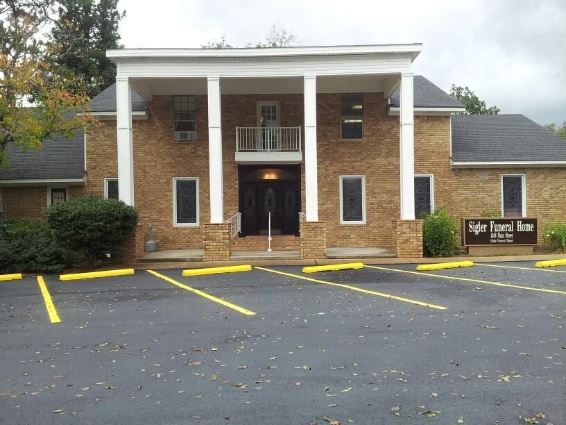 Brick building entrance with covered porch, brick columns, and empty yellow-lined parking spaces in front