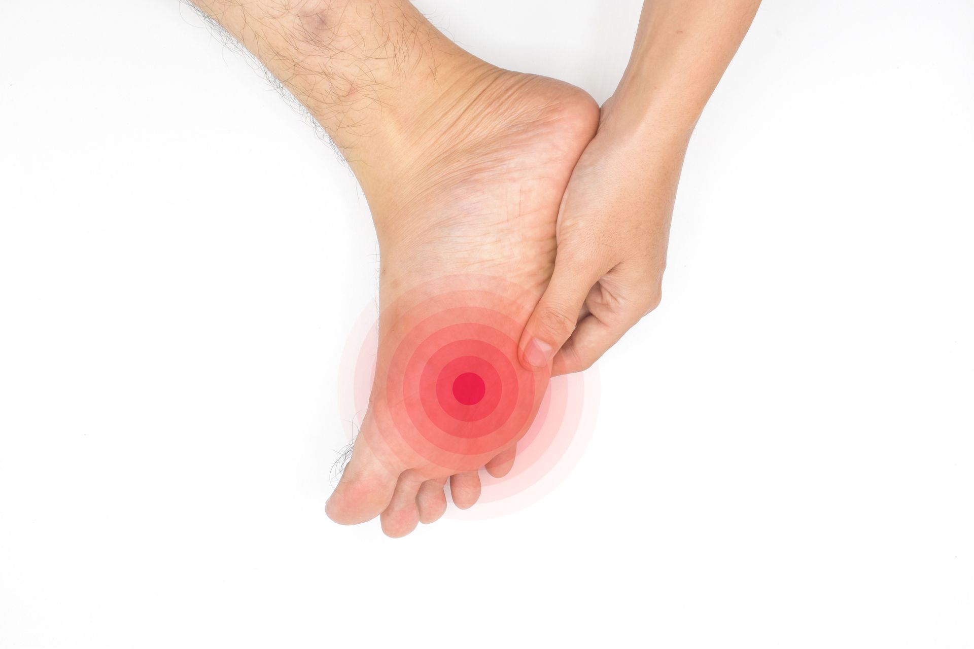 Foot with red pain circle, hand holding heel on white.