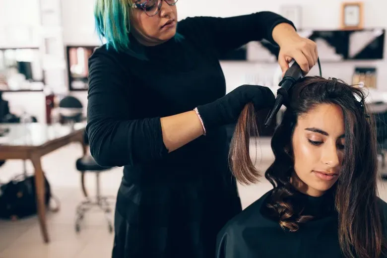 Hair Stylist Makes A Curl For Woman In Salon — Silver Sping, MD — Montgomery Beauty School
