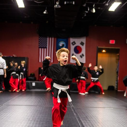 A group of kids are practicing martial arts in a gym