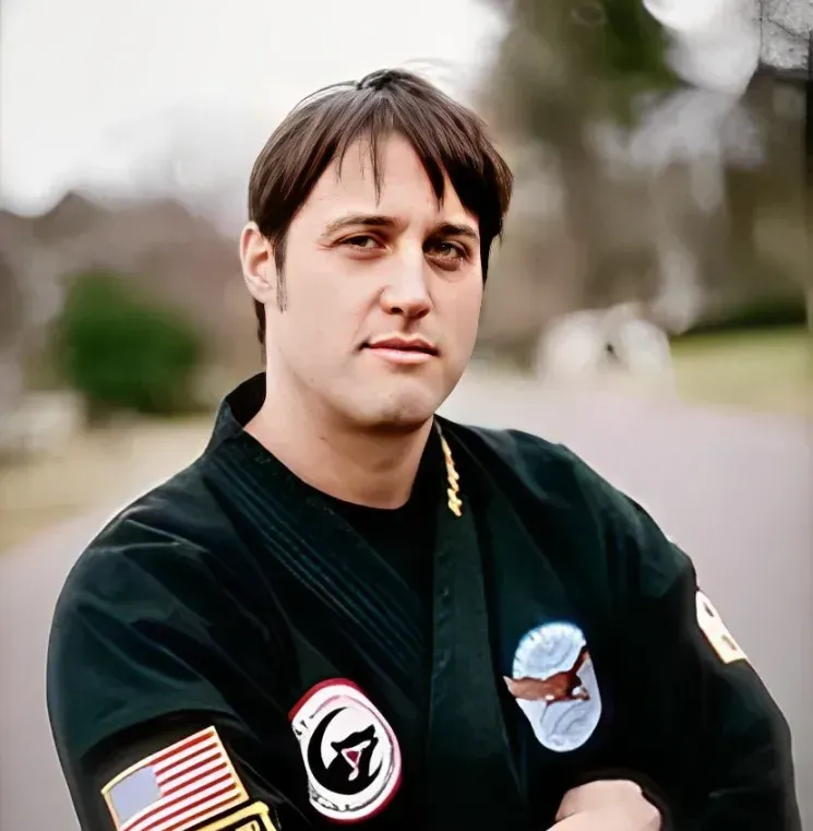 A man wearing a black karate uniform has a patch on his arm that says g.a.