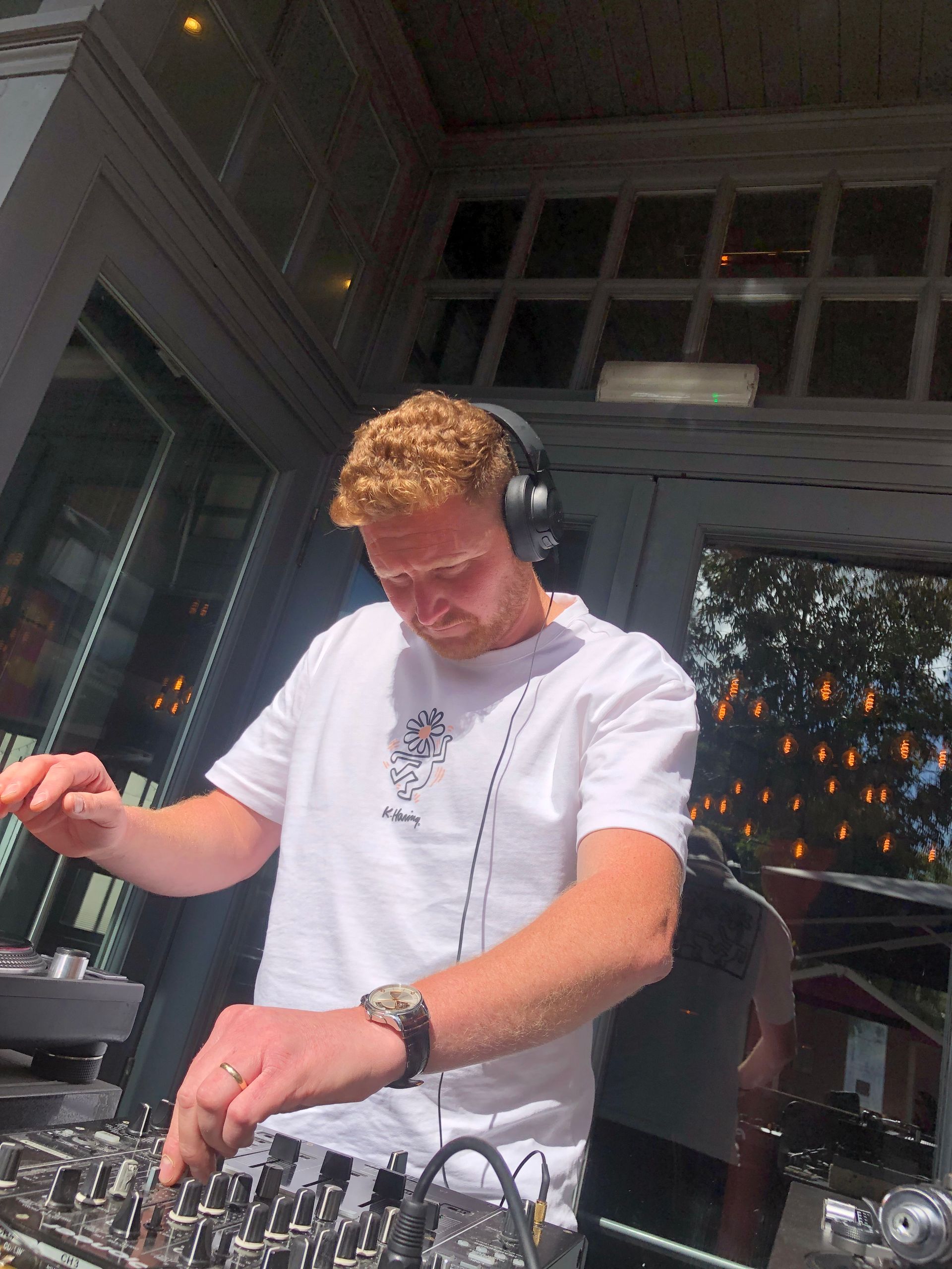 A man wearing headphones is playing music on a mixer.