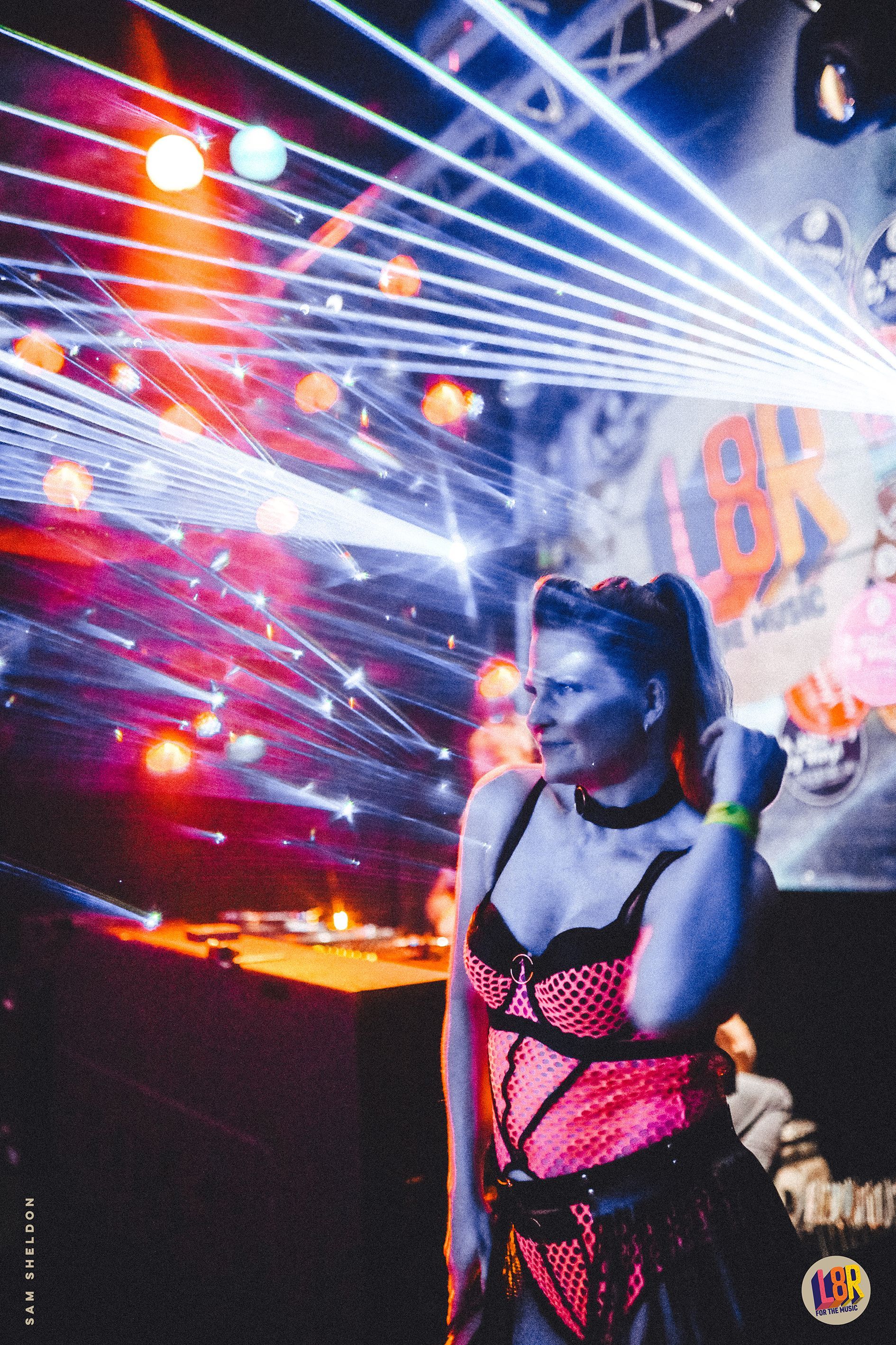 A woman in lingerie is standing in front of a stage in a club.
