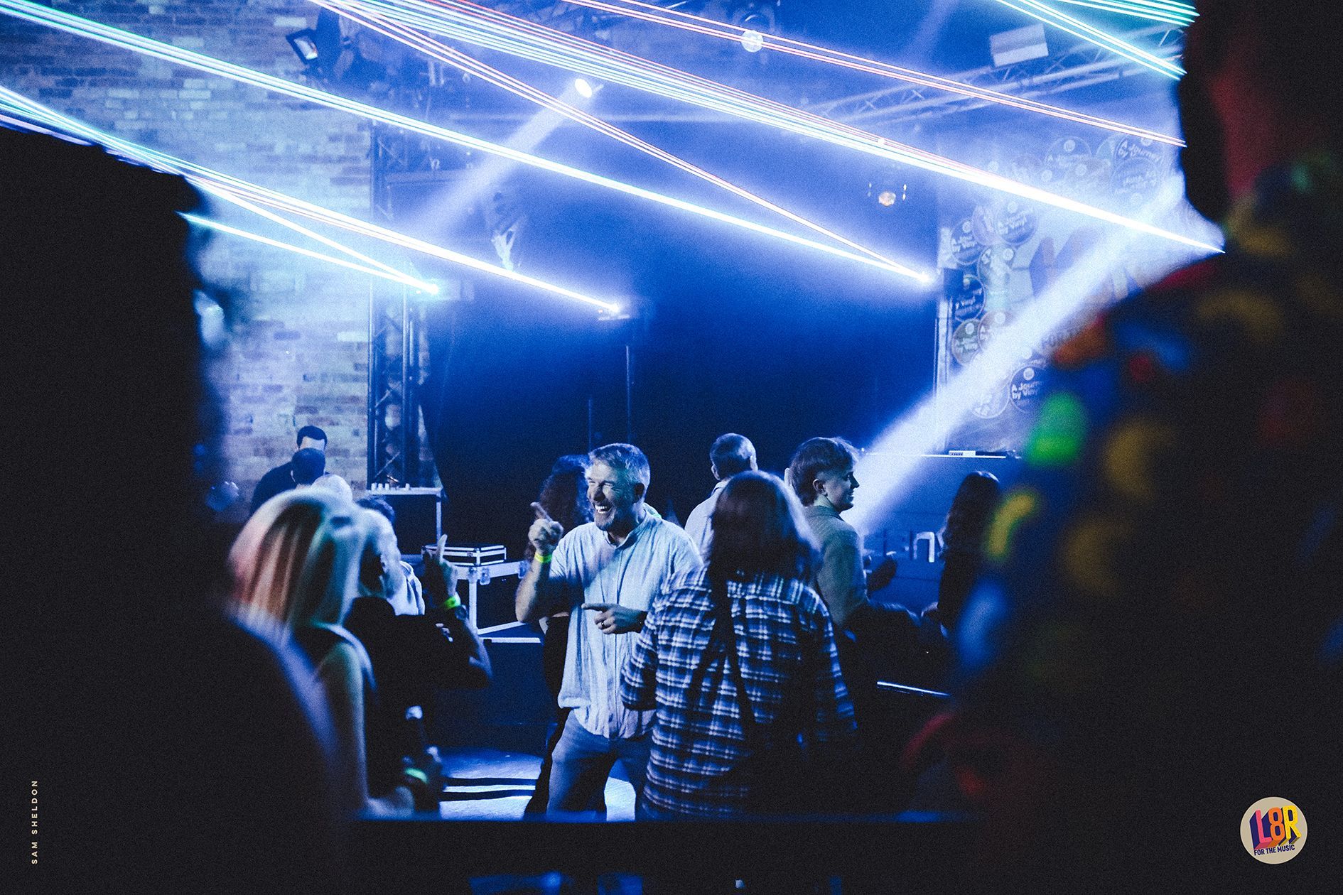 A group of people are dancing in a dark room with blue lights.