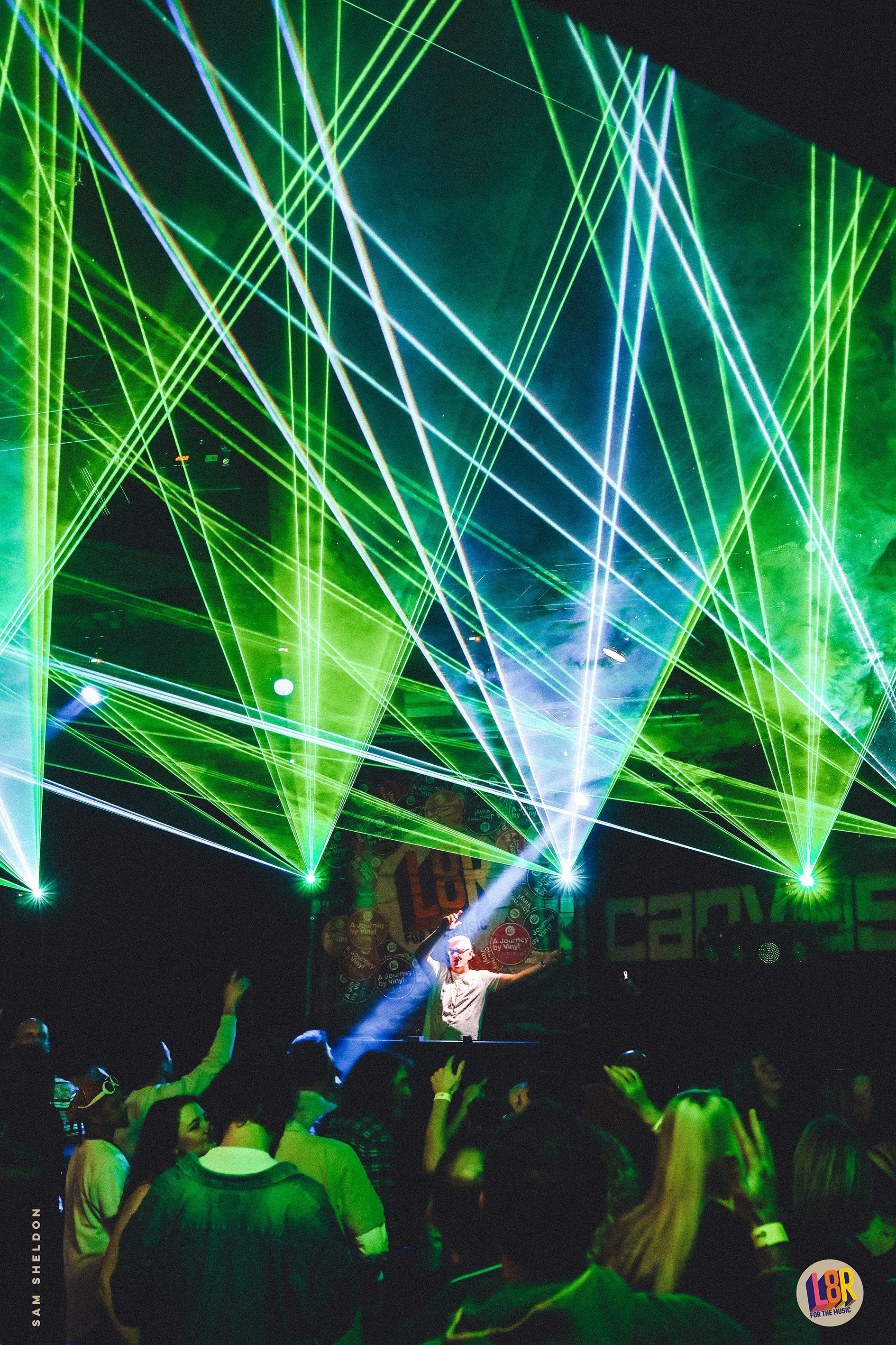 A group of people are dancing in front of a stage with green lights