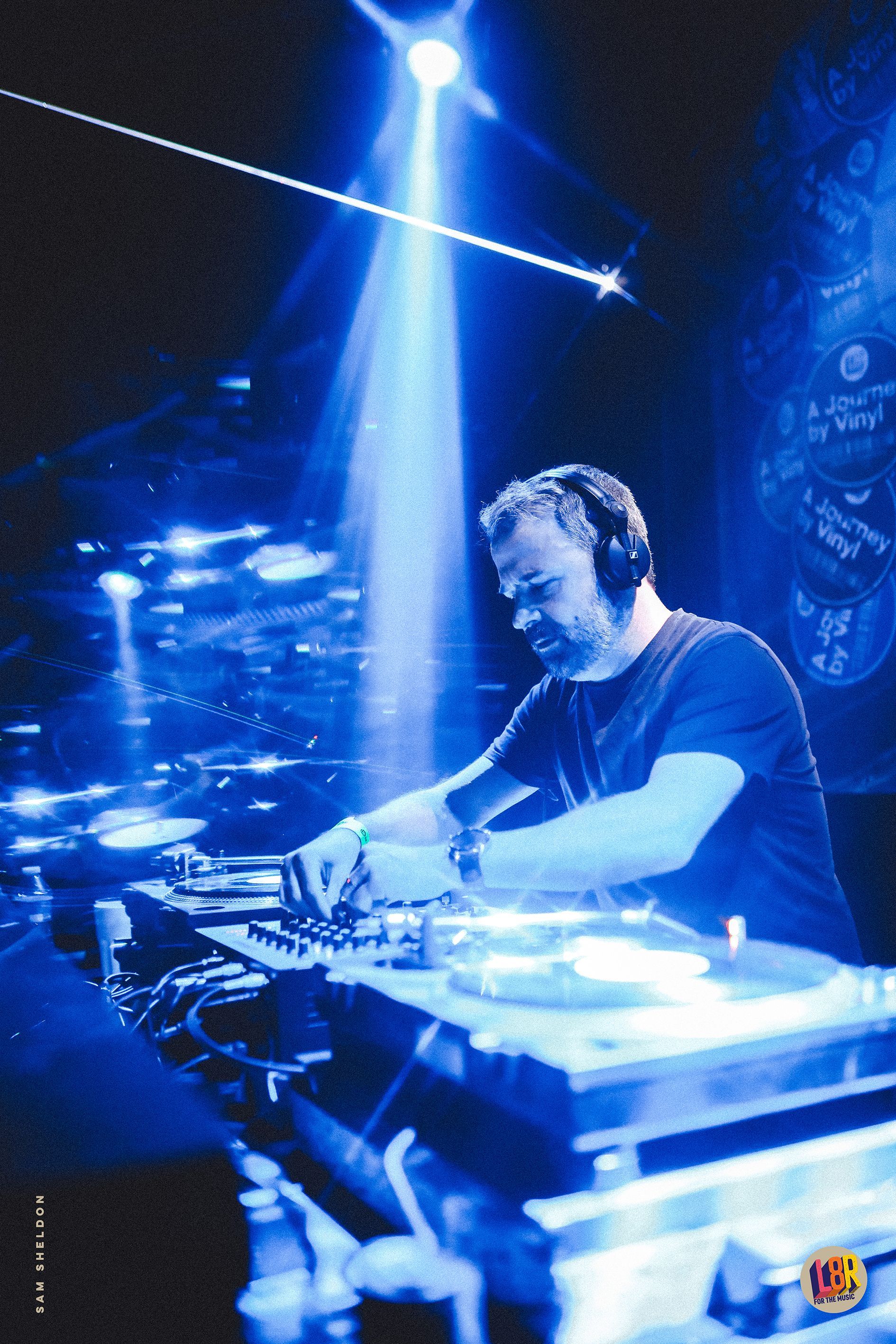 A man wearing headphones is playing music in a dark room.