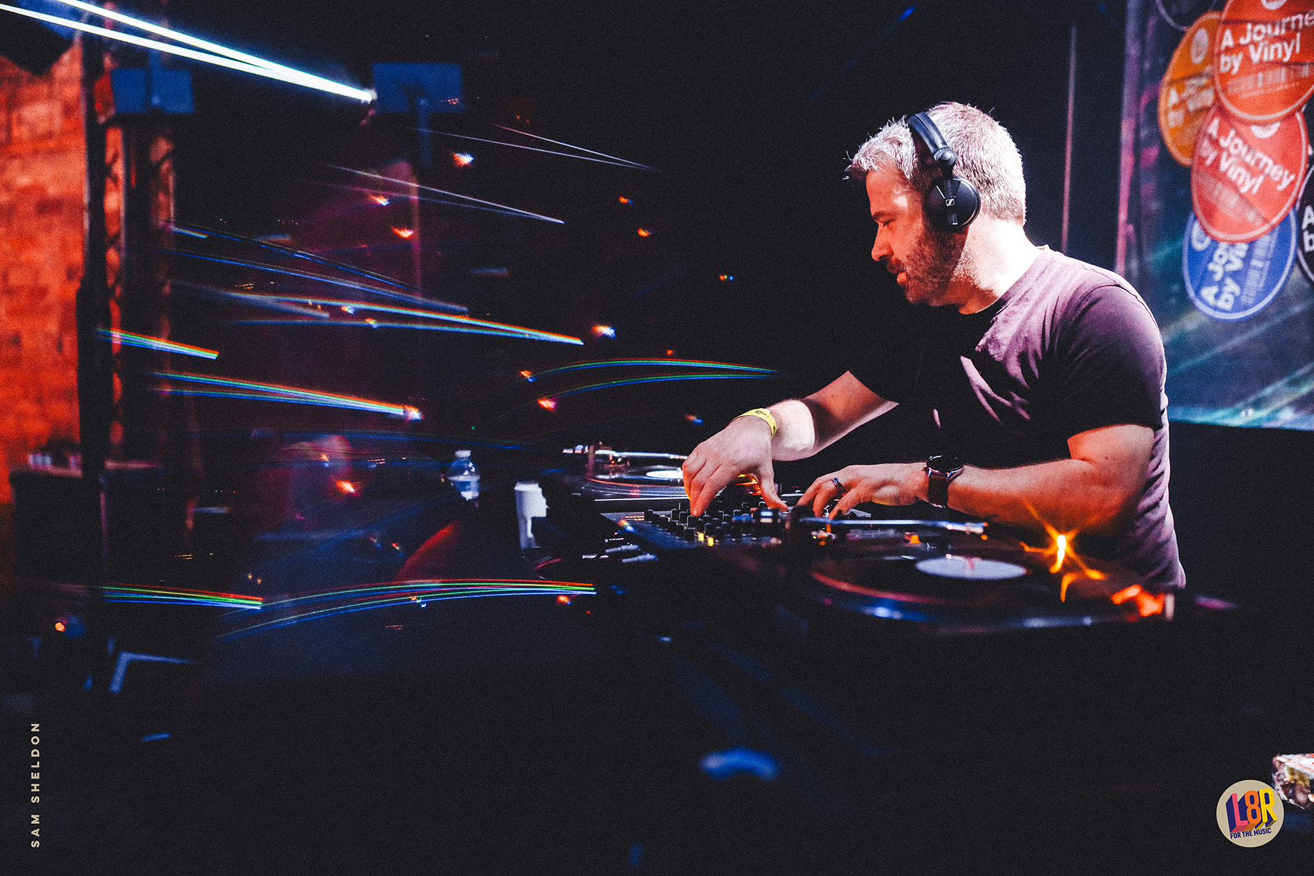 A man wearing headphones is playing music in a dark room