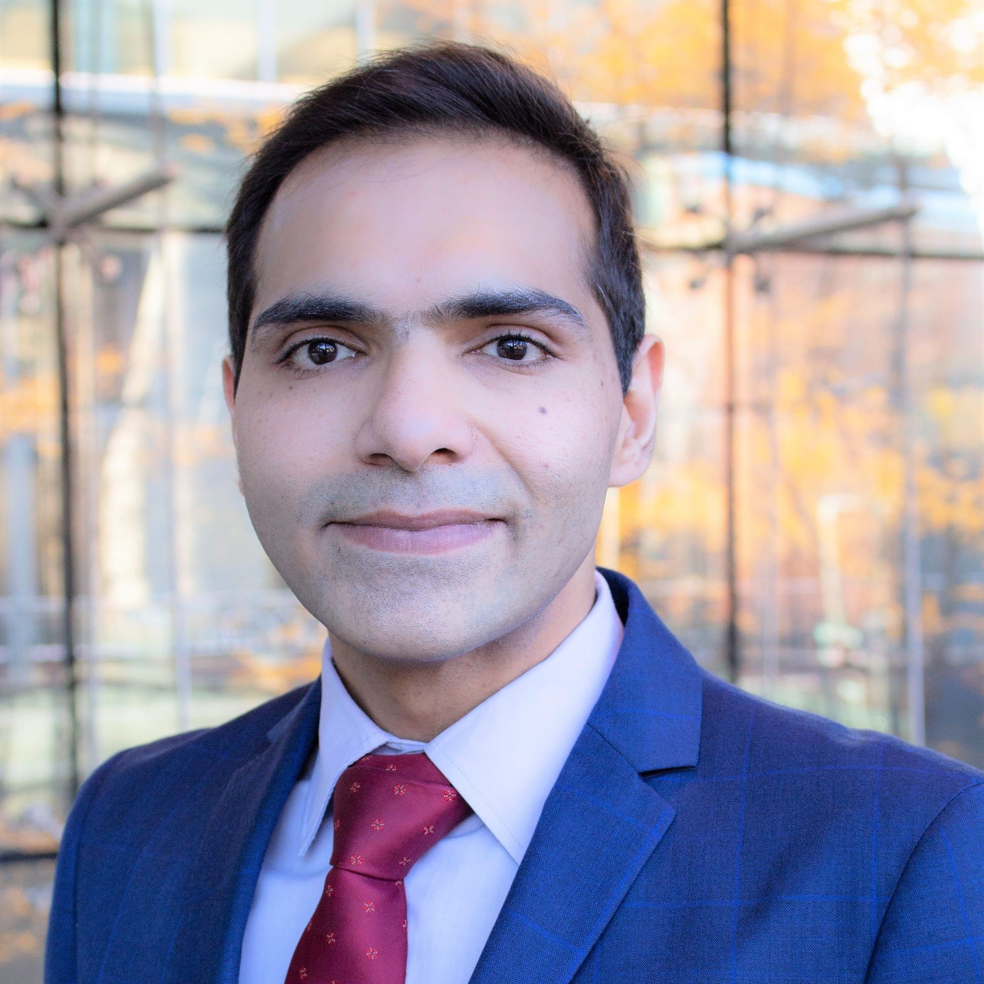 a man in a blue suit and red tie smiles for the camera