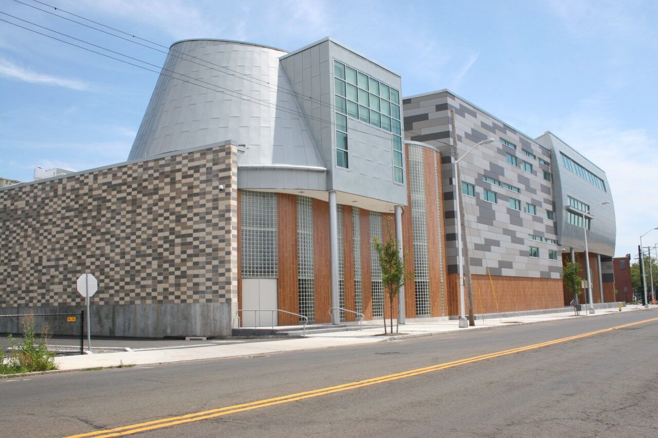 Modern building with patterned facade and glass entrance along an empty street