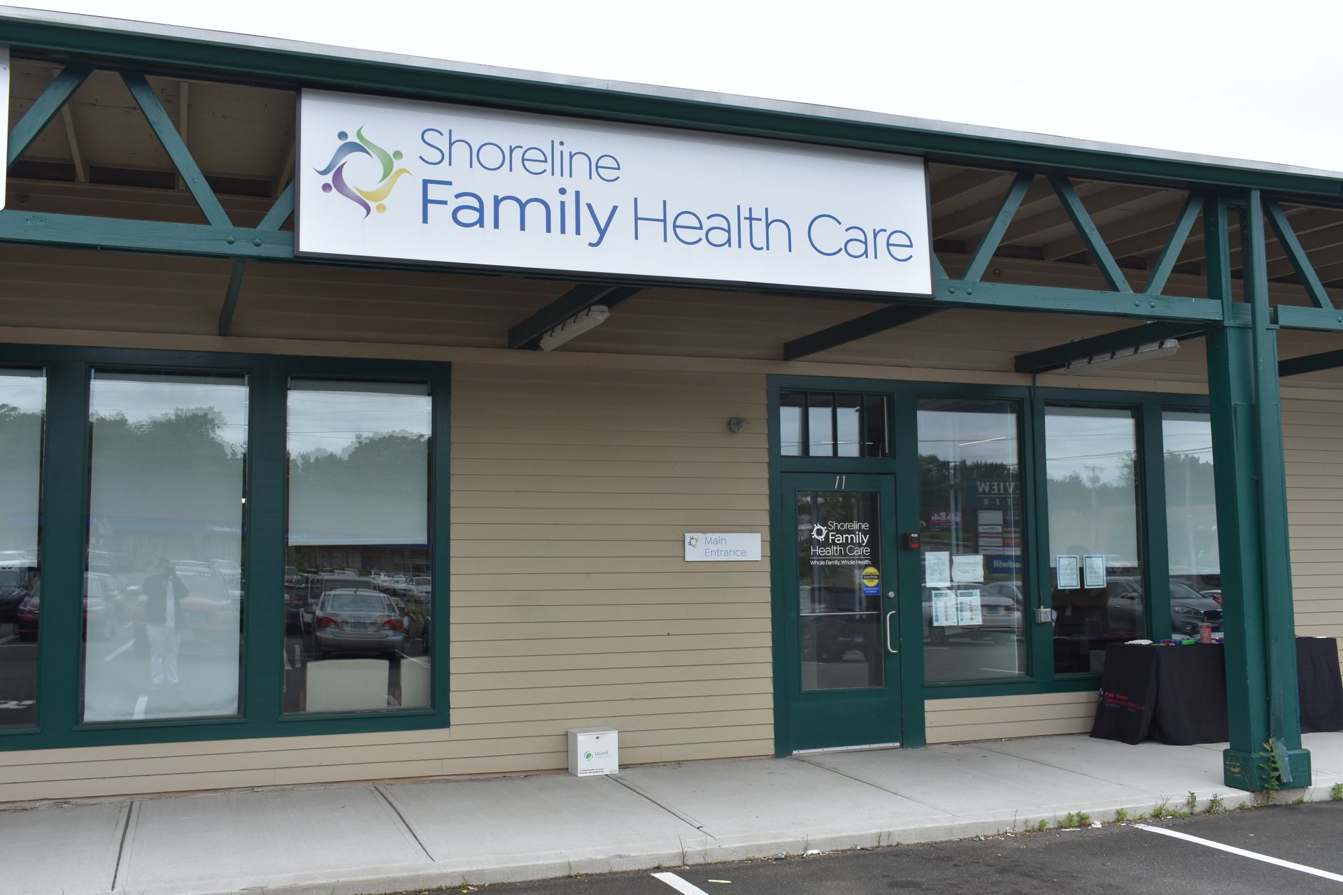 Shoreline Family Health Care clinic exterior with green doors and beige siding under a covered walkway