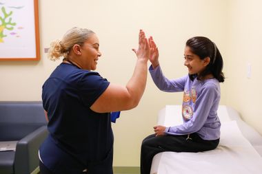 Two people in a clinic room high-five beside a treatment table
