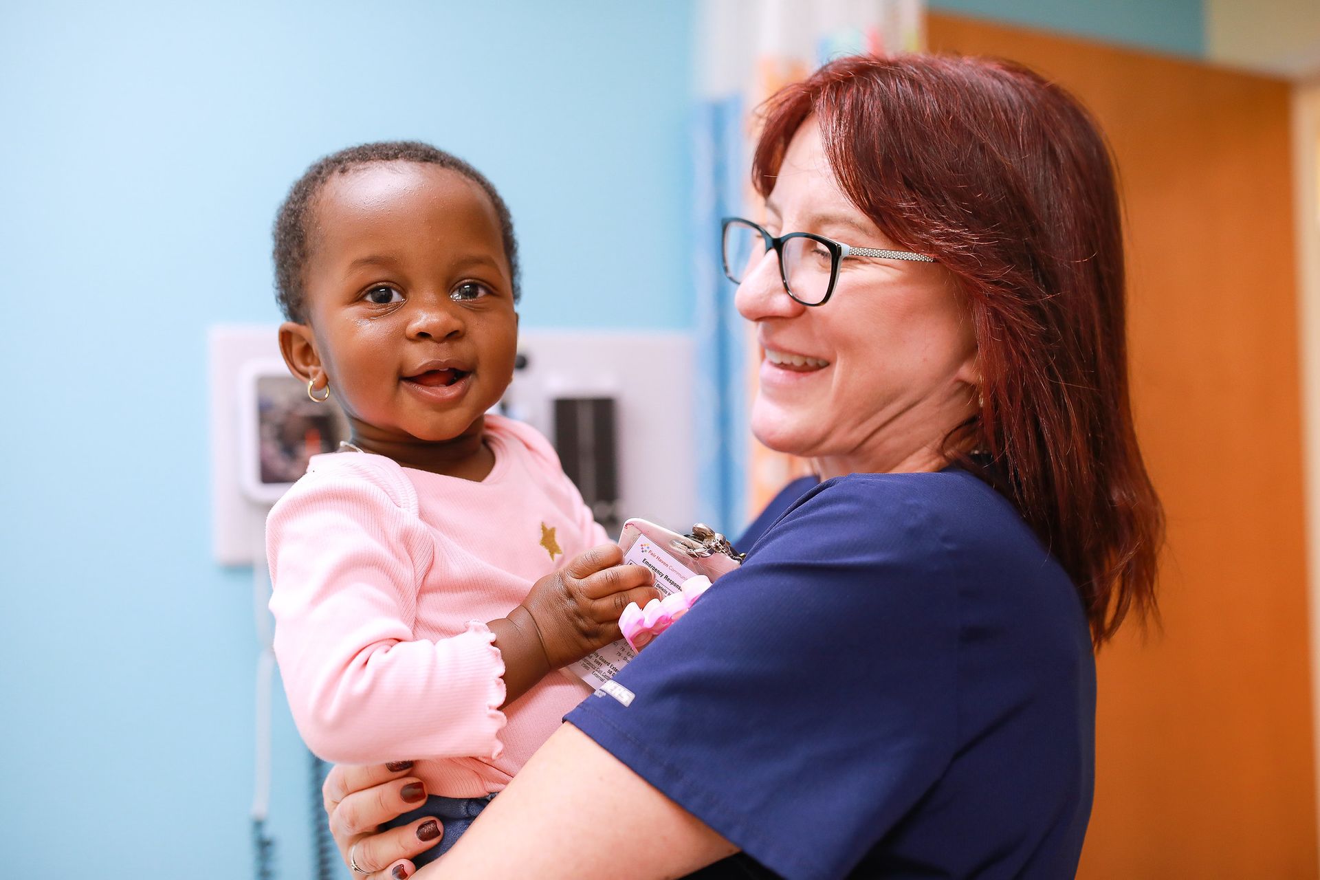 Woman holding a smiling toddler in a clinic room