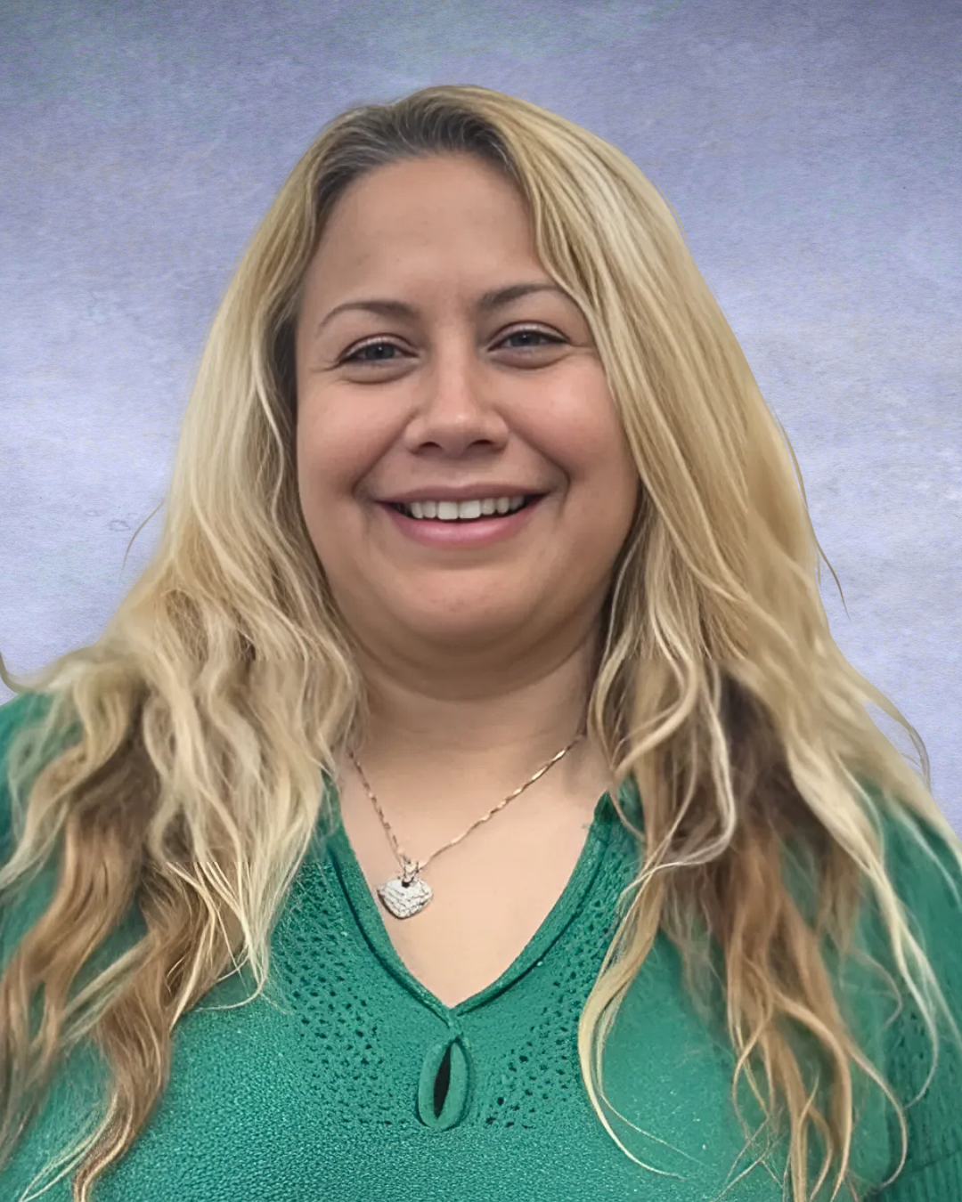 Smiling woman with long blonde hair wearing a green top against a gray background