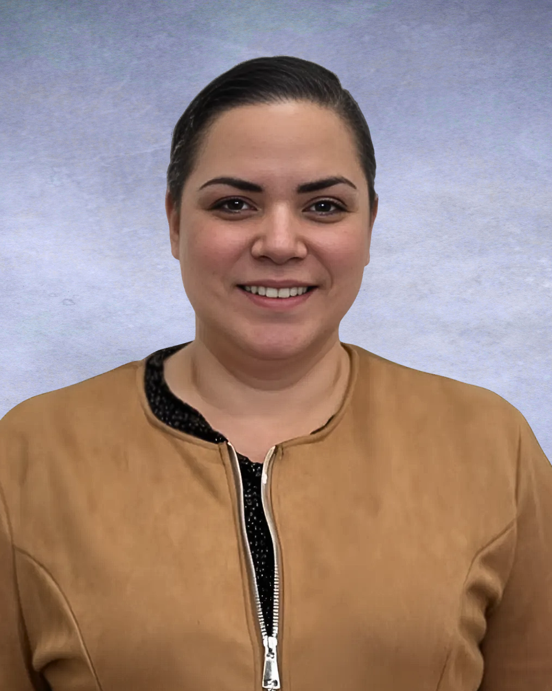 Smiling person in a tan jacket against a gray studio backdrop