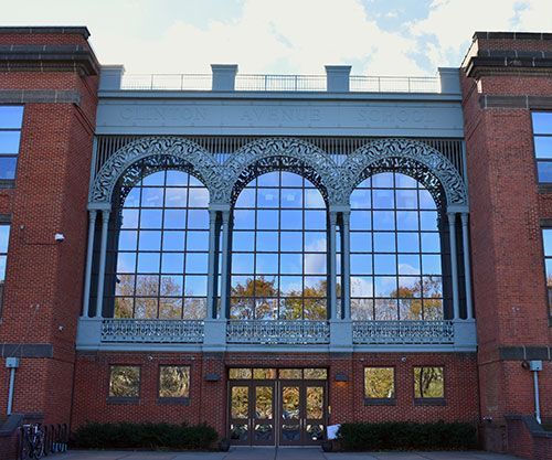 Red brick building facade with large arched windows and a central entrance
