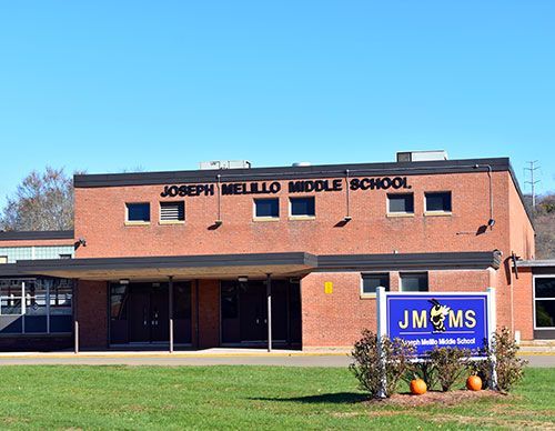 Brick school building with a JMMS sign and green lawn in front