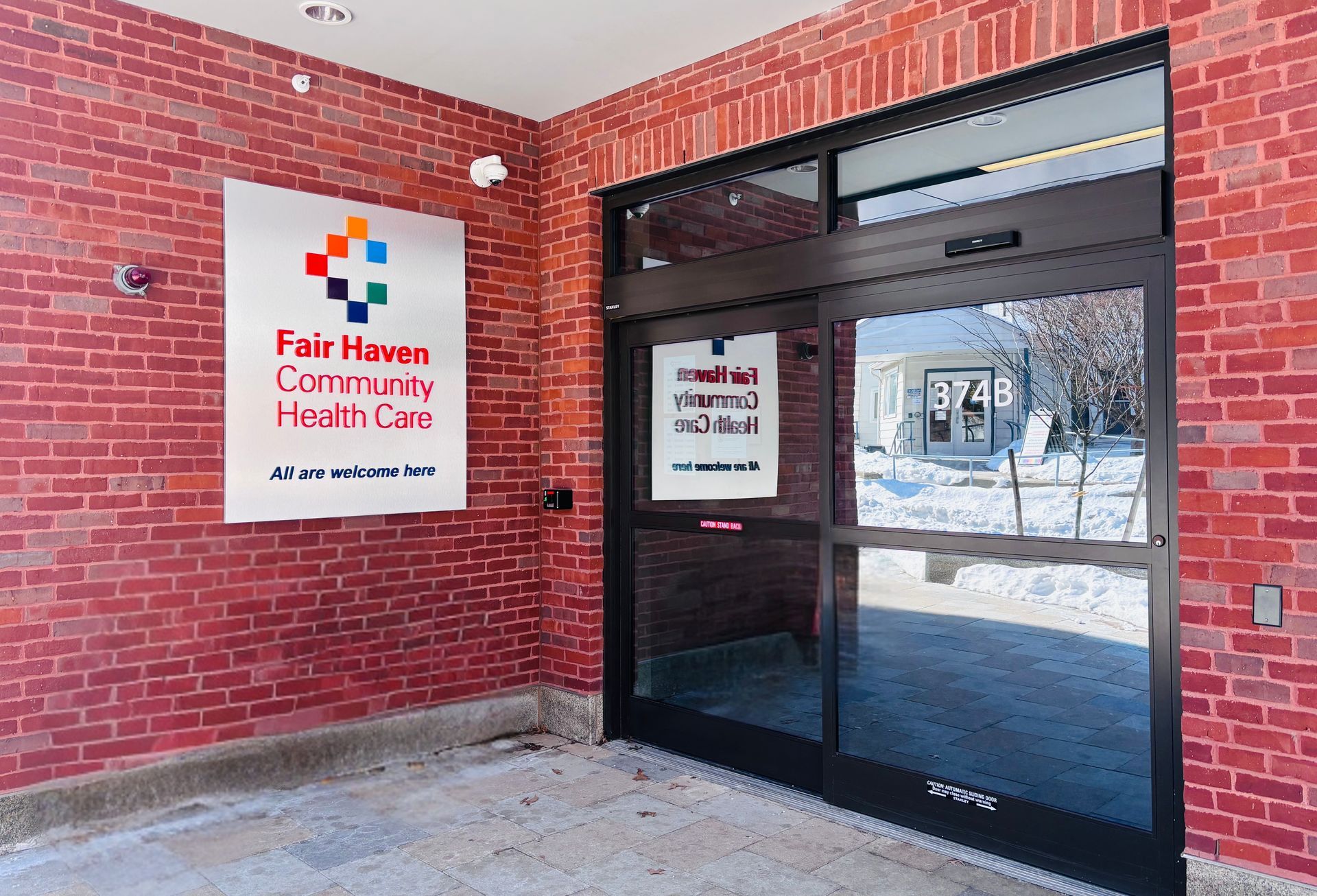 Fair Haven Community Health Care sign on red brick building entrance with glass doors