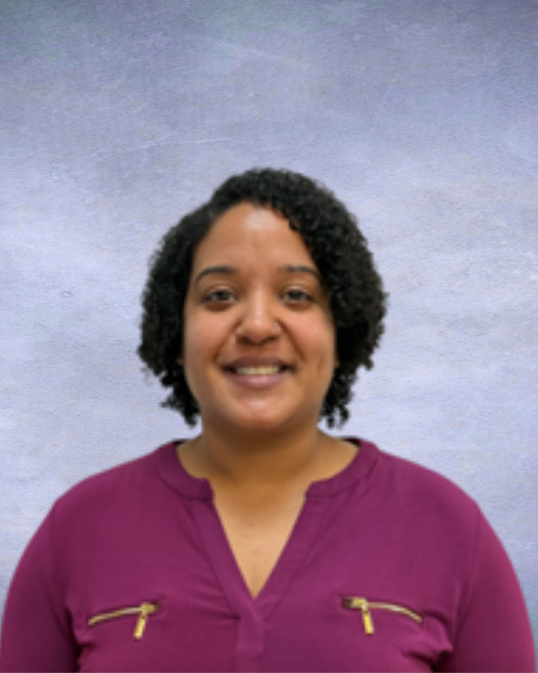 Smiling person in a magenta blouse against a light gray backdrop