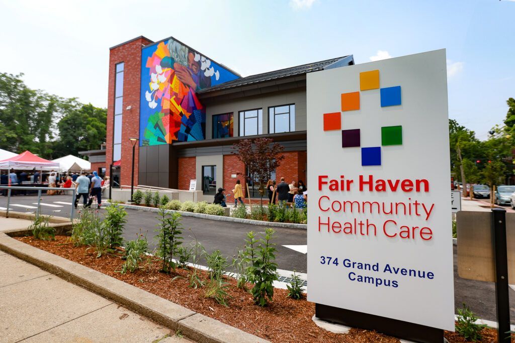 Fair Haven Community Health Care sign outside a modern building with colorful mural and landscaping