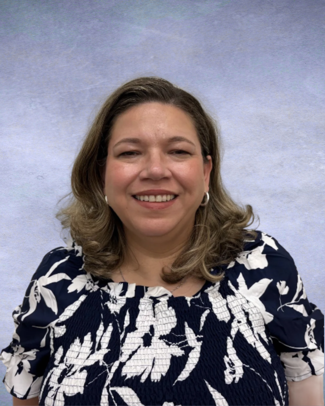 Smiling woman in a navy floral blouse against a light gray backdrop
