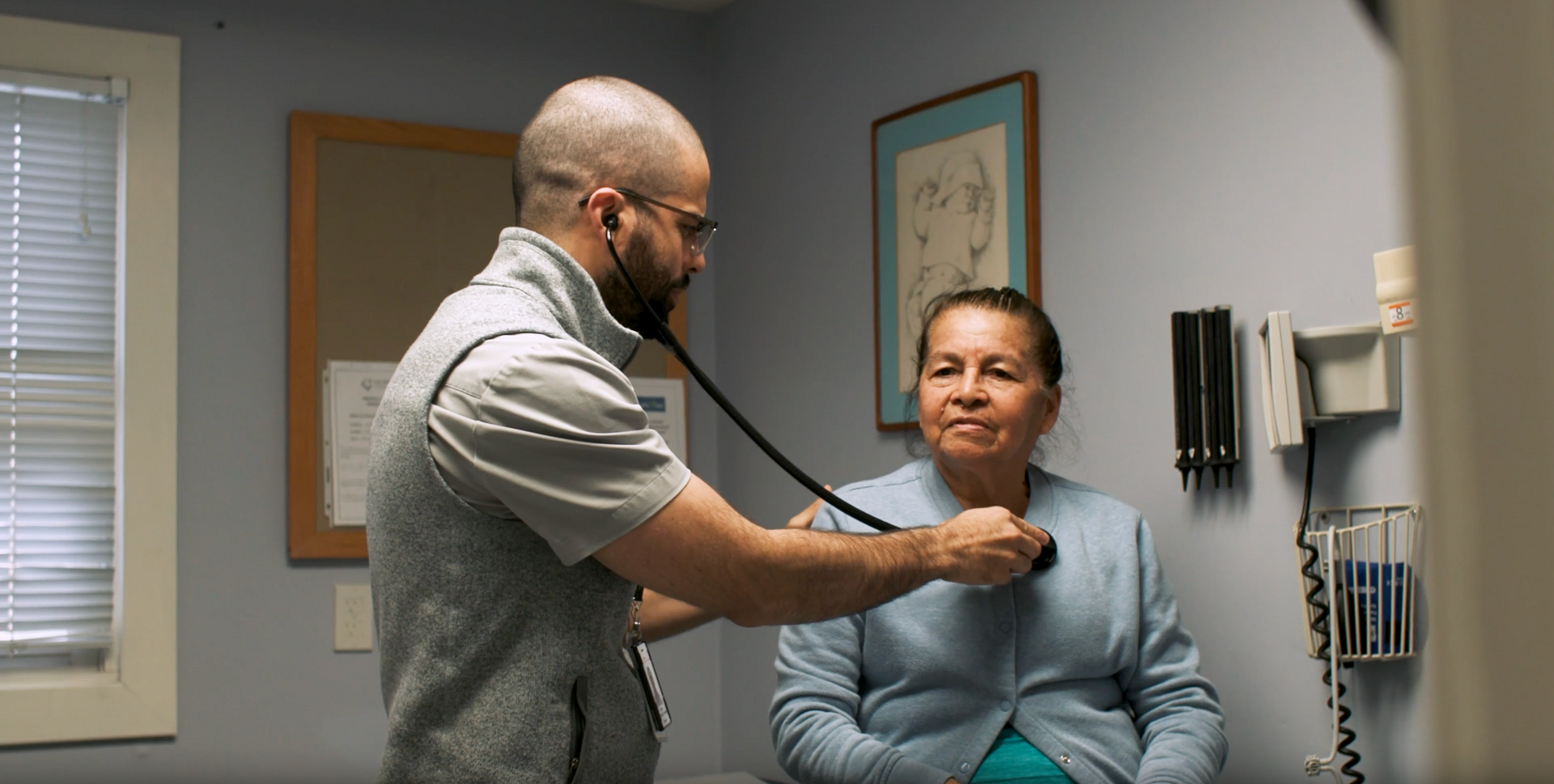 Doctor examining a patient with a stethoscope in a clinic exam room
