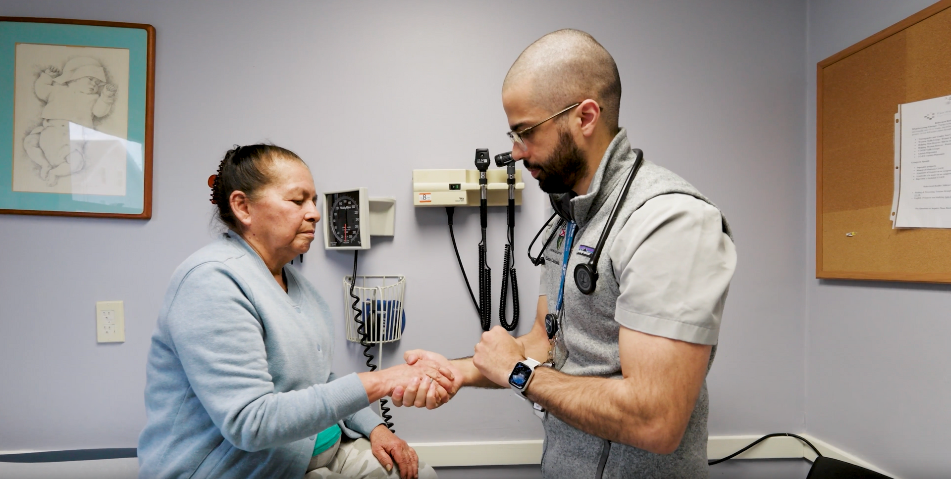 A medical provider examines a patient's wrist in a clinical exam room.