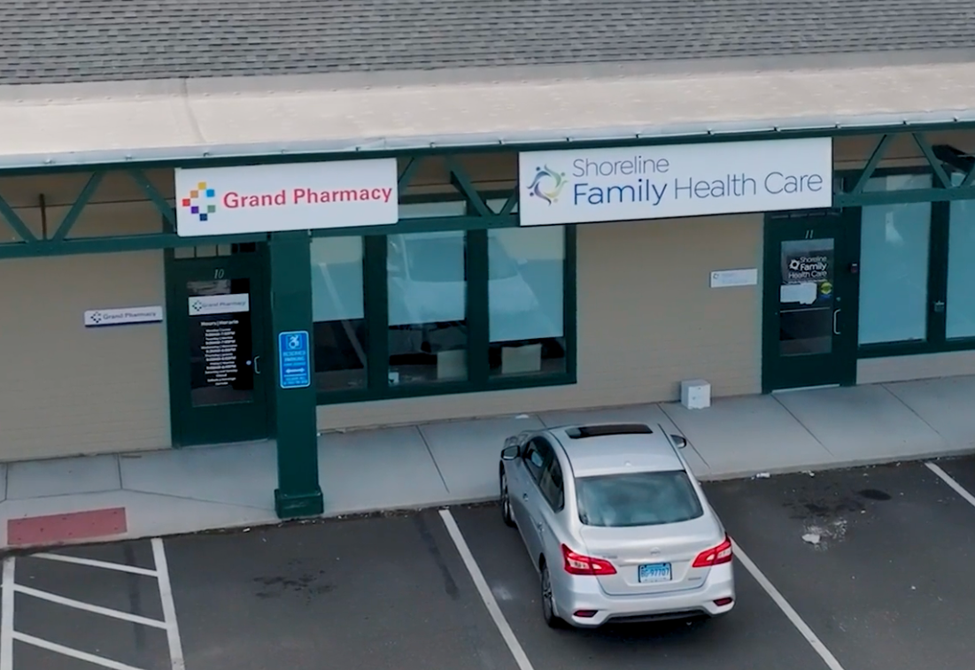 Entrance to Grand Pharmacy and Family Health Care with a silver car parked in front