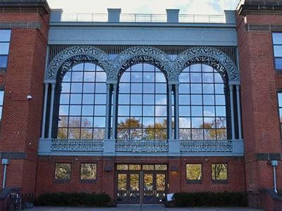 Brick building facade with large arched windows and central glass entrance