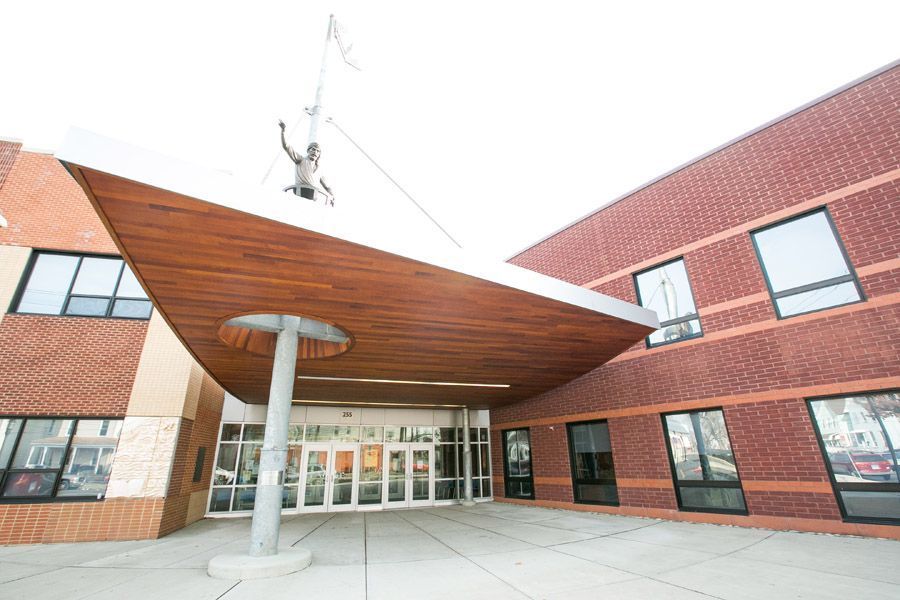Modern brick building entrance with a red metal canopy and glass doors