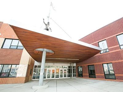 Modern brick building entrance with a wood canopy and glass doors