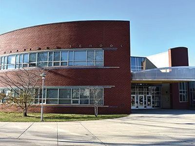 Modern brick building with curved glass windows and a covered entrance on a sunny day
