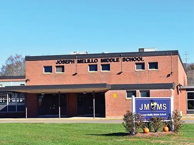 Brick school building with a JMMS sign and green lawn in front
