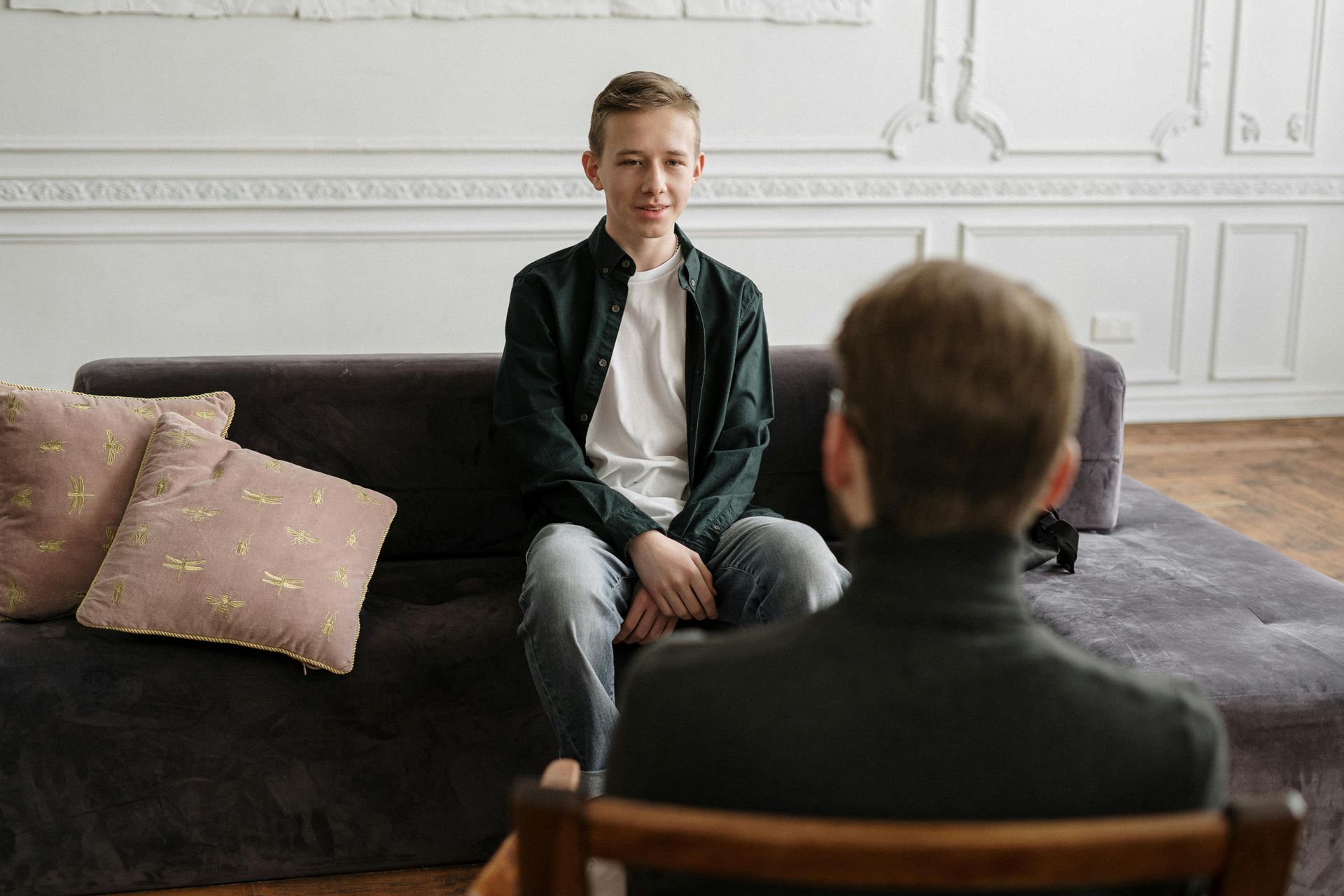 Two people seated in a bright living room, one facing the other during a conversation.