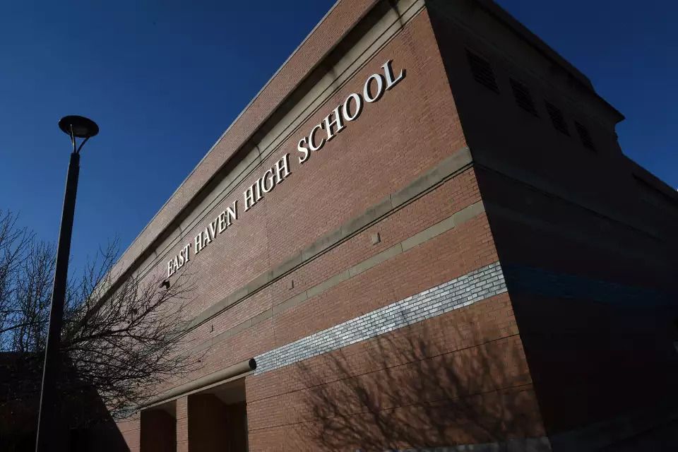 Exterior of a brick elementary school building with school sign on the wall and a lamppost nearby