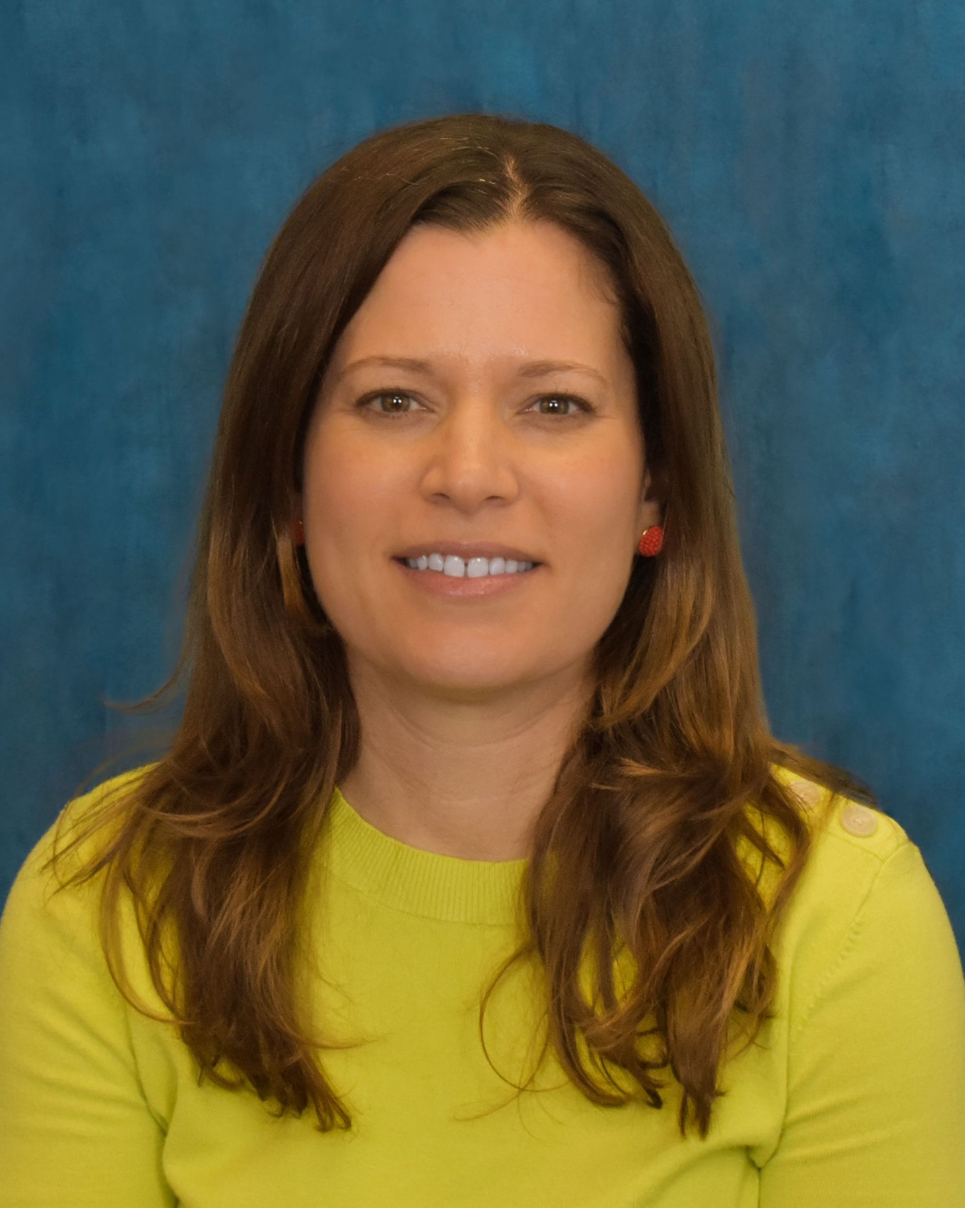 Portrait of a smiling person in a yellow top against a blue background