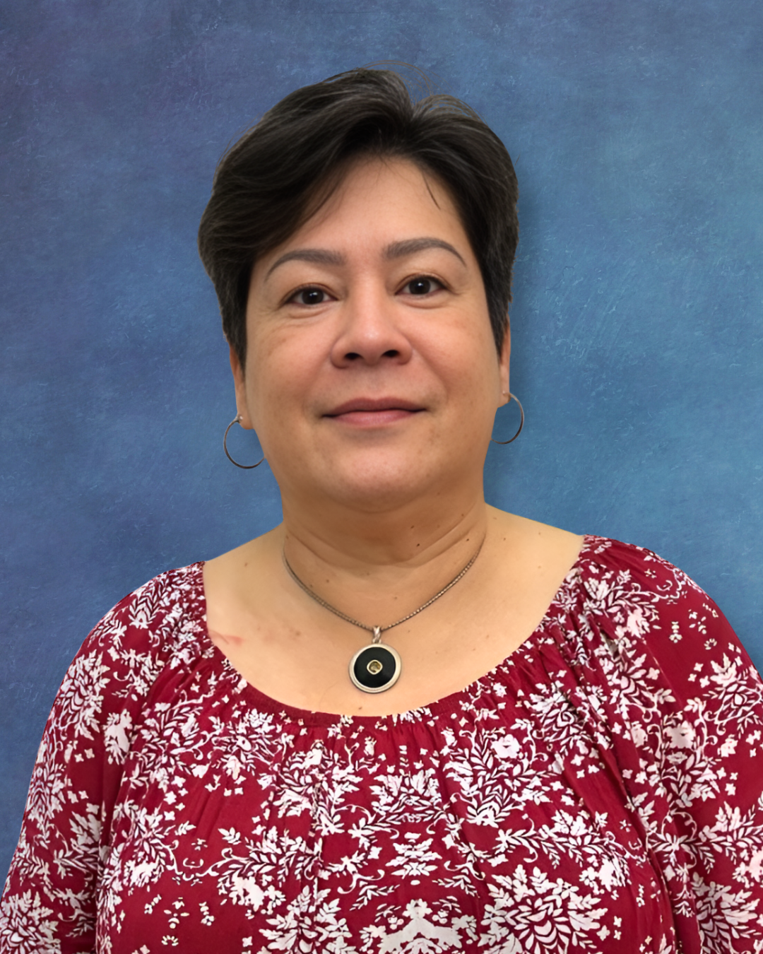 Portrait of a woman in a red floral top against a blue studio backdrop