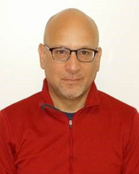 Man wearing glasses and a red zip-up jacket against a plain light background