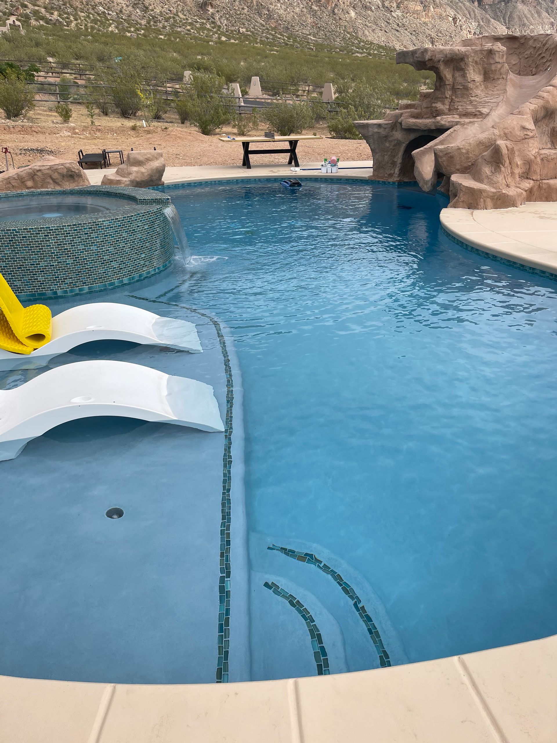 Pool with curved waterslide and rock backdrop under a bright blue sky