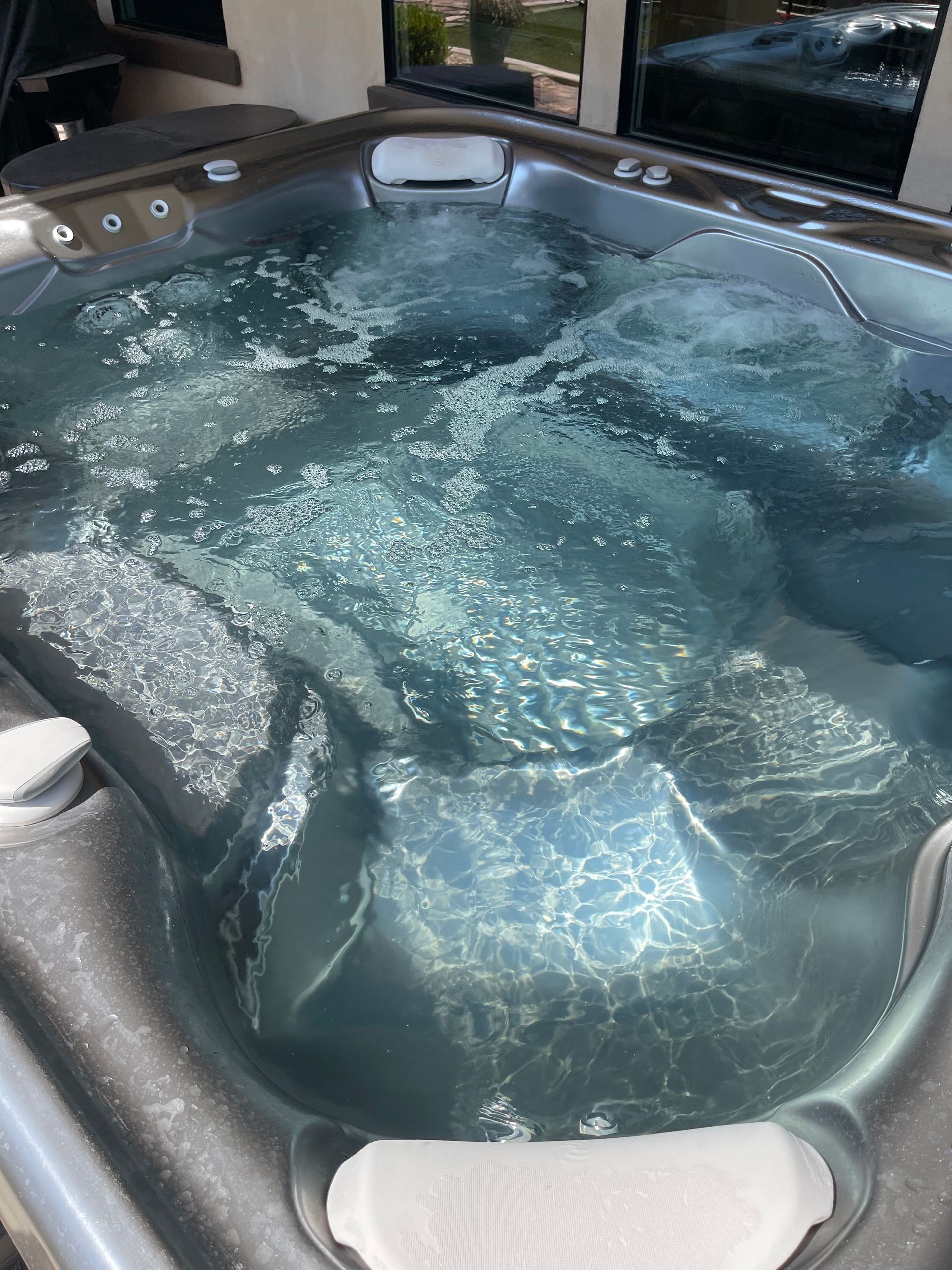 Water-filled hot tub with bubbling jets and gray seats indoors