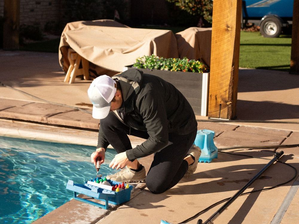 Person kneeling by a pool, working on a blue tool box near the water's edge