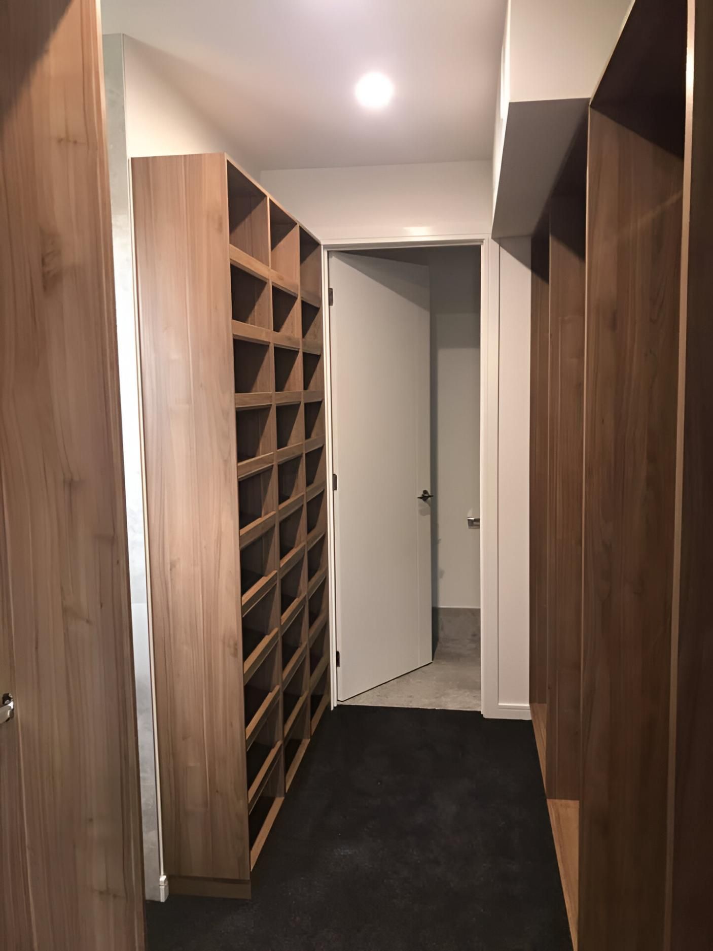 A Hallway with Wooden Shelves and A White Door — Inovative Interiors In Cardiff, NSW