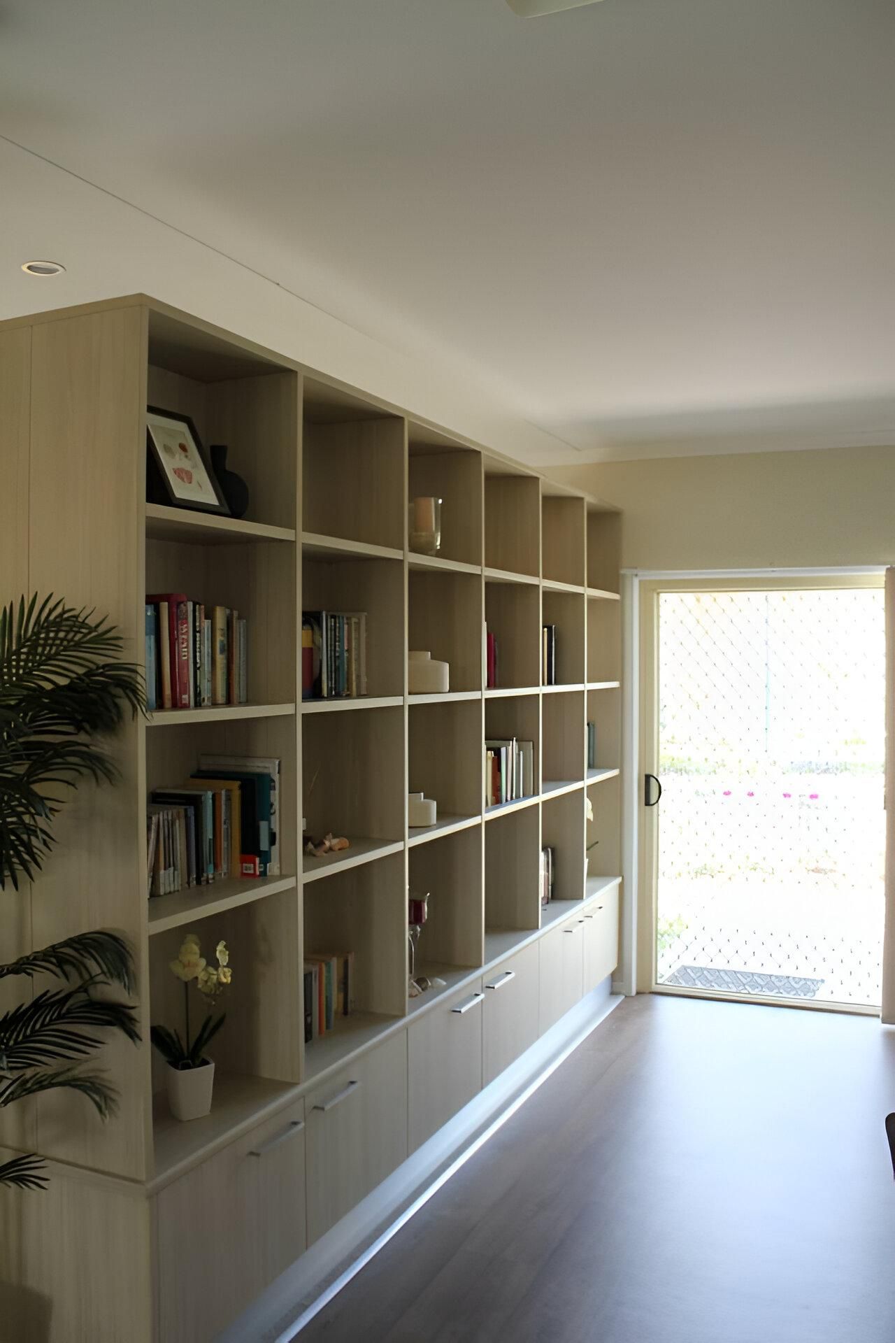 A Living Room with A Large Bookshelf Filled with Books — Inovative Interiors In Lake Macquarie, NSW