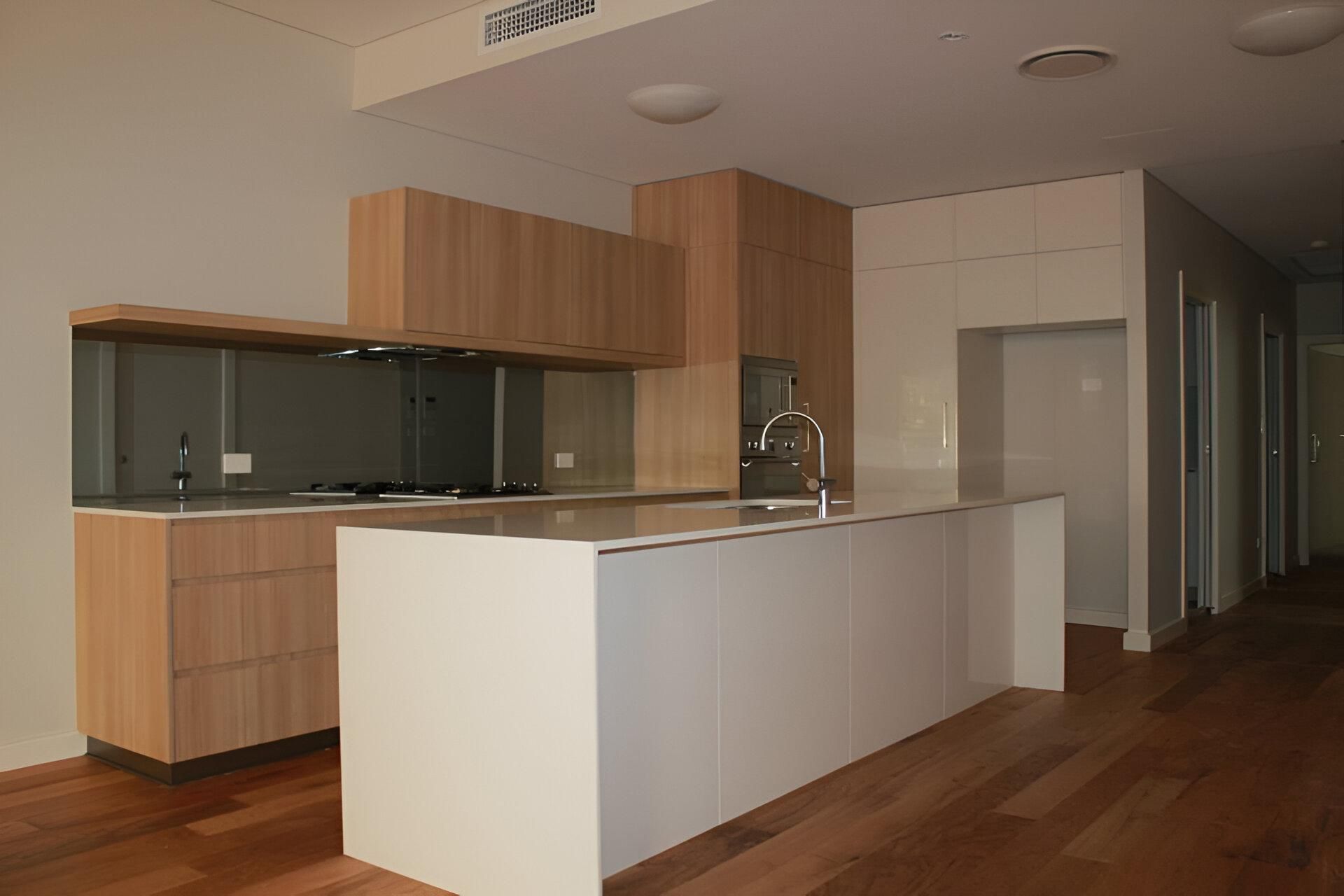 A Kitchen with A Large Island and Wooden Cabinets — Inovative Interiors In Lake Macquarie, NSW