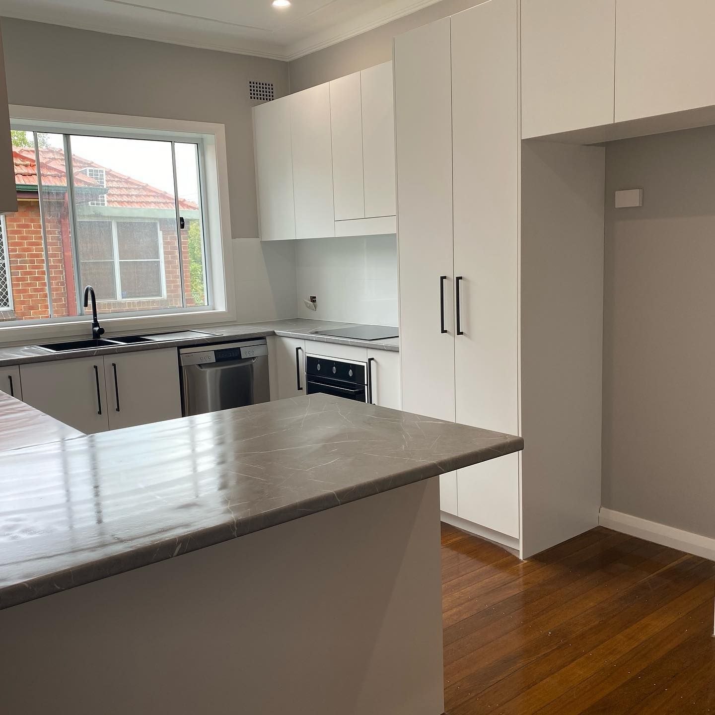 A Kitchen with White Cabinets, Stainless Steel Appliances and A Large Island — Inovative Interiors In Lake Macquarie, NSW
