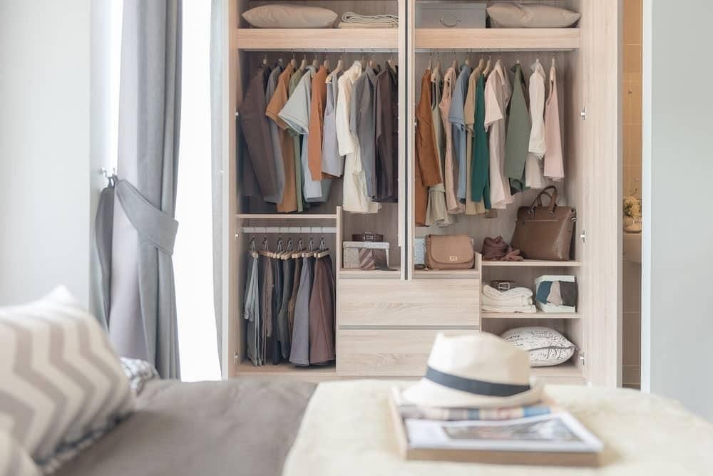 A Bedroom with A Closet Filled with Clothes and A Hat on A Table — Inovative Interiors In Cardiff, NSW